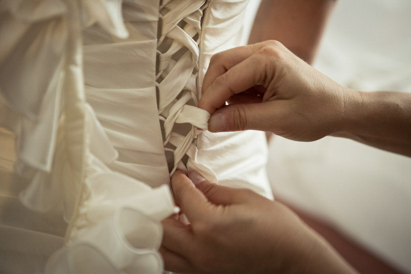 Fotografo matrimonio Torino: preparativi per l'allacciamento del vestito da sposa